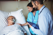Nurse Consoling Senior Patient With Doctor