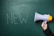 © New Africa - Woman holding megaphone and word NEW on chalkboard