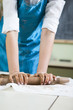 © danmorgan12 - Extreme Closeup of Hands of Female Professional in Apron Rolling Out a Piece of Clay with Rolling Pin in Workshop.