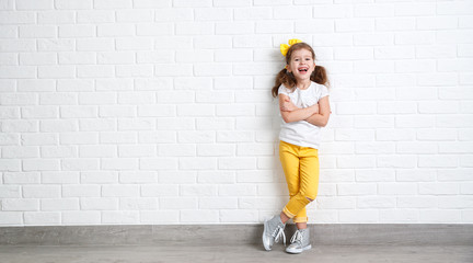 Wall Mural - happy funny child girl   near an empty brick wall.