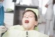 © qunica.com - Boy with perfect teeth at the dentist doing check up with the clinic at the background - oral hygiene health care concept