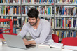 © Jale Ibrak - Male Student Typing on Laptop in the University Library