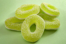 Chewy Sweets And Apple Flavoured Gummy Candy Concept With Close Up On Sweet And Sour Green Rings Covered In Granulated Sugar Isolated On A Green Background