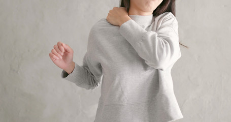 Wall Mural - Woman feeling pain on shoulder over gray background