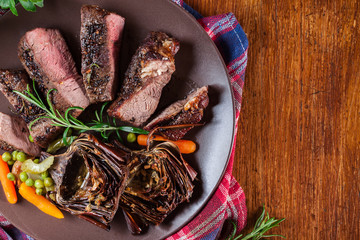 Wall Mural - Slices of beef steak served with baked artichoke