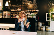 © bnenin - Beautiful woman drinking coffee and using phone at the restaurant.