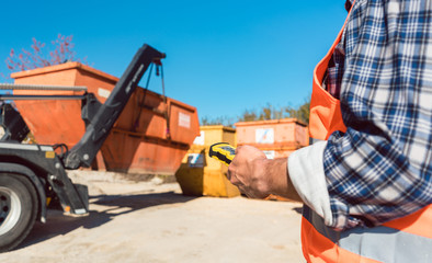 Man loading of construction debris container on truck with remote control 