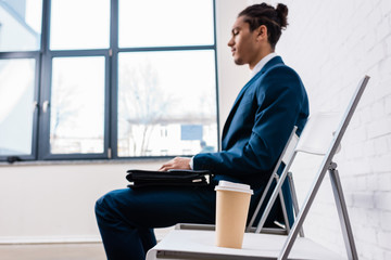 Wall Mural - Businessman sitting on chair and waiting by coffee cup