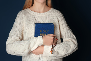 Canvas Print - Religious young woman with Bible on dark background, closeup