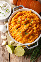 Wall Mural - Delicious puree of sweet potato with garlic and onion close-up in a bowl. Vertical top view