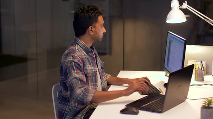 technology, deadline and people concept - programmer with laptop computer working at night office
