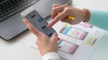 technology and people concept - creative woman with smartphone and laptop computer working on interface design at office and making notes
