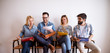 © Dusan Petkovic - Group of young cheerful people holding colourful folders while sitting in a chair sharing notes and discussing in the waiting room for an exam.