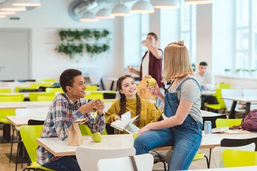 happy high school students taking lunch together at school cafeteria