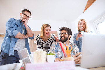 Group of young cheerful dedicated business team discussing further steps while one of them is worried.