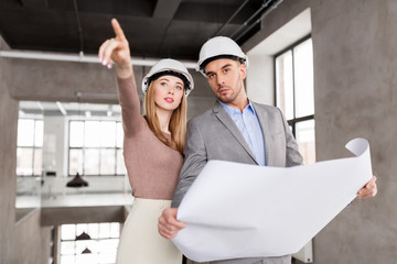 architecture, construction business and people concept - architects with blueprint and helmets at of