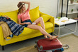 © LIGHTFIELD STUDIOS - beautiful happy girl in hat holding passport and air ticket while sitting on sofa with baggage