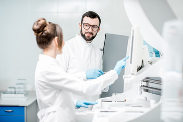 Laboratory assistants in unifrom working with professional medical analizer at the laboratory