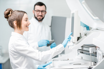 Wall Mural - Laboratory assistants in unifrom working with professional medical analizer at the laboratory