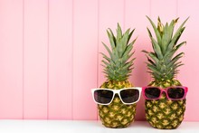 Hipster Pineapples With Trendy Sunglasses Against Pink Wood Background. Minimal Summer Concept.