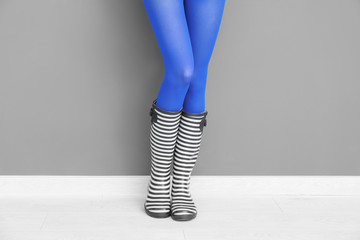 Canvas Print - Beautiful woman in stylish gumboots near color wall