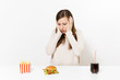 © ViDi Studio - Shocked woman put hands on head at table with burger french fries cola in glass bottle isolated on white background. Proper nutrition or American classic fast food. Advertising area with copy space.