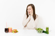 © ViDi Studio - Woman put hands on head with green detox smoothies, salad in glass bowl, cucumber, burger, cola in bottle isolated on white background. Proper nutrition, healthy lifestyle, fast food, choice concept.