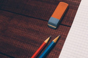 Bright used colorful pencils next to a blank sheet of paper. Work supplies stationery on a wooden texture table. Trendy minimalism. Concept of a modern freelancer workplace. Rustic cozy atmosphere