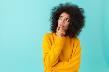 Wall Mural - American woman in colorful shirt looking upward remembering or reflecting, isolated over blue background