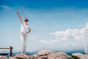 Pretty young woman standing on top of mountain