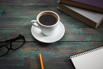 A cup of coffee in the workplace on a wooden table. A cup of coffee in the workplace on a wooden table. The concept of working outside the office