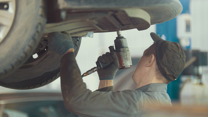 Mechanic unscrews detail of car in hood - automobile service repairing, close up