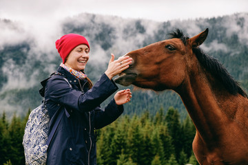 Wall Mural - Caucasian female hiker bonding with horse in mountain valley