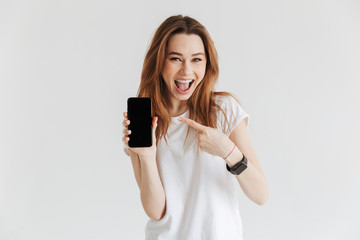 Happy woman in casual clothes showing blank smartphone screen