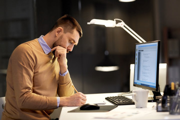 it, deadline and people concept - man with notepad working on computer code at night office