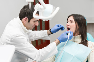 Wall Mural - Ultrasonic cleaning of teeth with water pressure in a patient woman, sitting in the dental chair