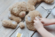 A girl sews a bear toy. Handicraft with children. Child fills the toy with a sintepon.
