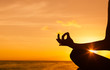 Hand meditating against ocean sunset. 