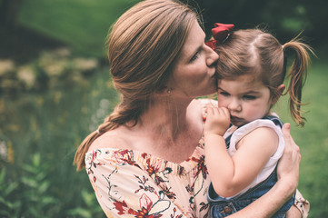 Loving mother comforting daughter with a kiss