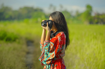 sweet young Asian Chinese or Korean woman on her 20s taking picture with photo camera smiling happy in beautiful nature landscape in holidays