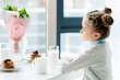© LIGHTFIELD STUDIOS - side view of child sitting at table with bouquet of flowers, glass of milk and homemade pancakes