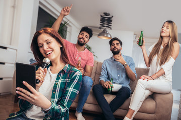 Wall Mural - Group of friends playing karaoke at home. Concept about friendship, home entertainment and people