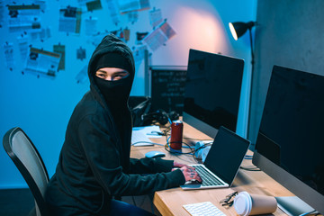 Wall Mural - female hacker in mask developing malware at workplace