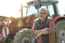 Farmer Standing By Tractor Outside The Barn