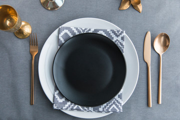 top view of black empty plate, napkin and old fashioned tarnished cutlery on tabletop