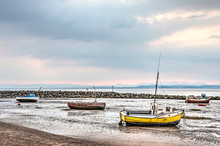 Four Little Fishing Boats Temporarily Stranded On The Beach At Morecambe, Lancashire, England During Low Tide At Sunset