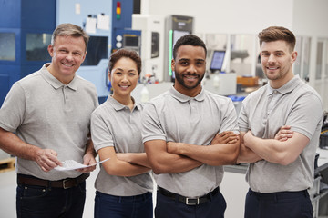 Portrait Of Engineering Team On Factory Floor Of Busy Workshop