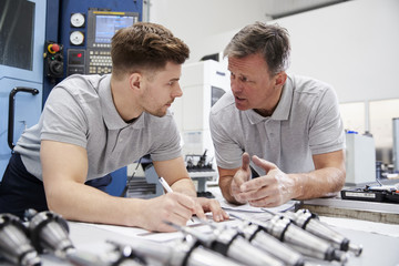 Wall Mural - engineer showing apprentice how to measure cad drawings