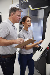 Wall Mural - engineer training female apprentice to use cnc machine in factory