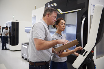 Wall Mural - engineer training female apprentice to use cnc machine in factory